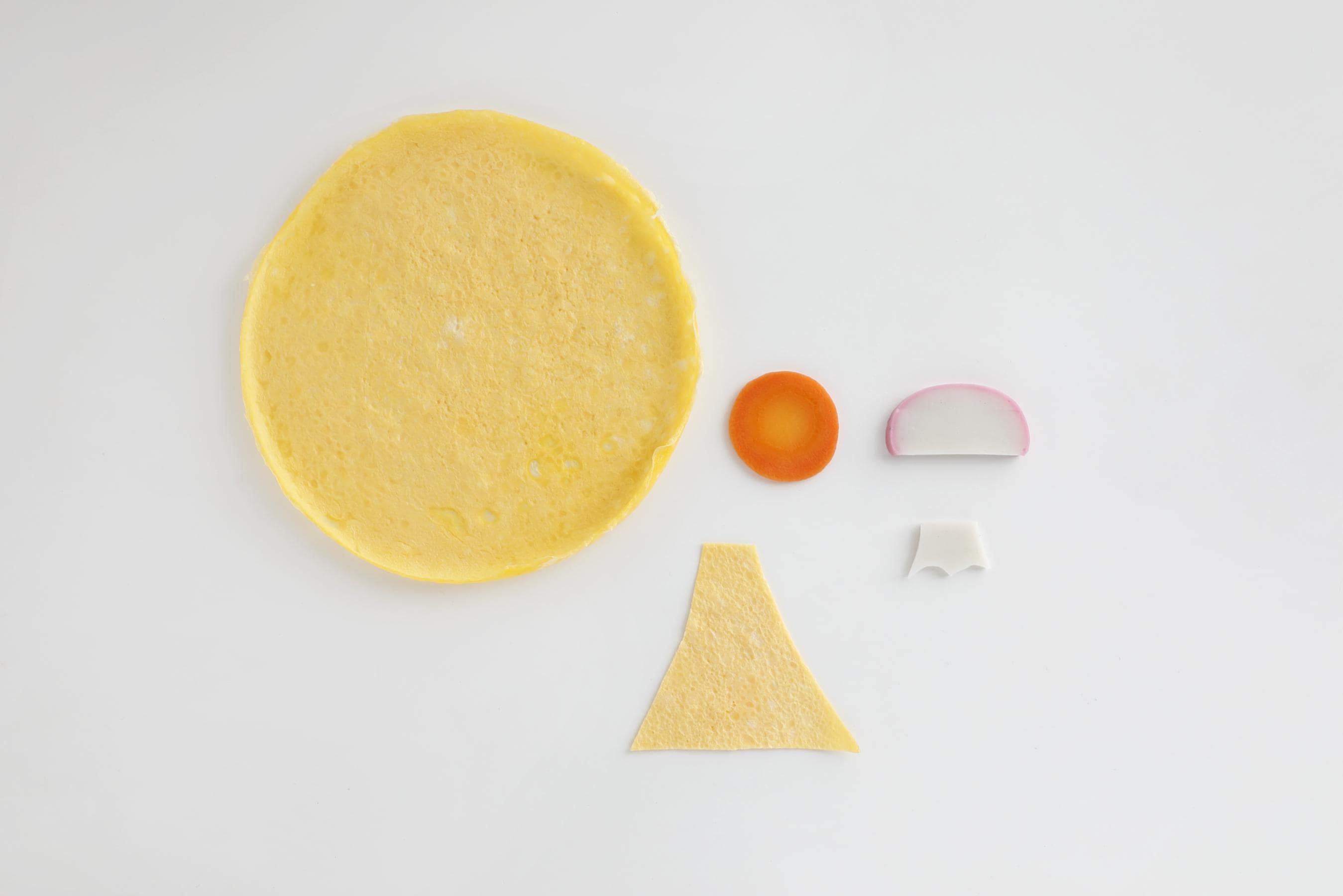 Cut the thin omelet in the shape of Mt. Fuji, the white part of the kamaboko for the snow peaks, and the carrot slice for the sun.