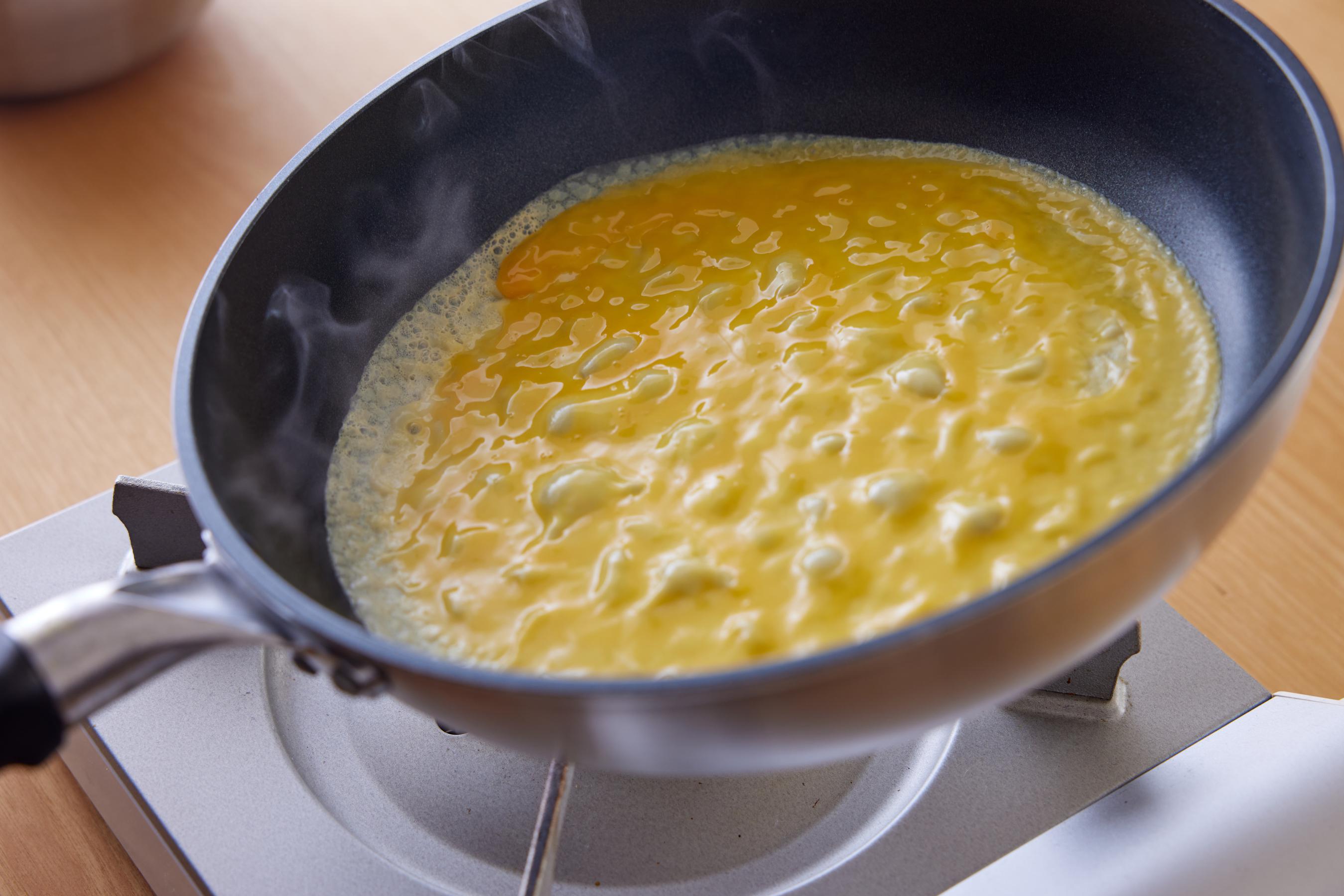 spreading egg mixture in a fry pan