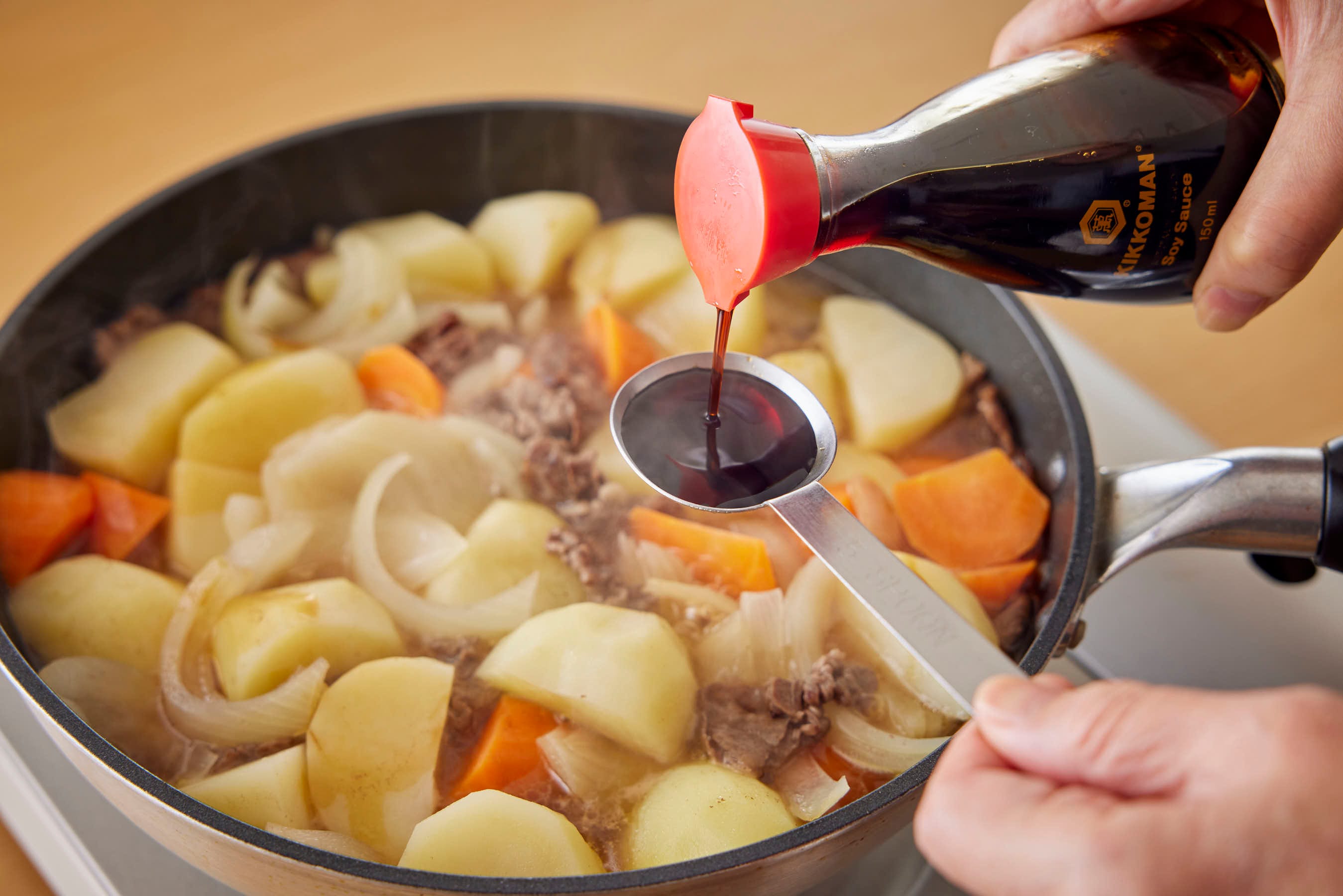 Adding Kikkoman Soy Sauce to nikujaga