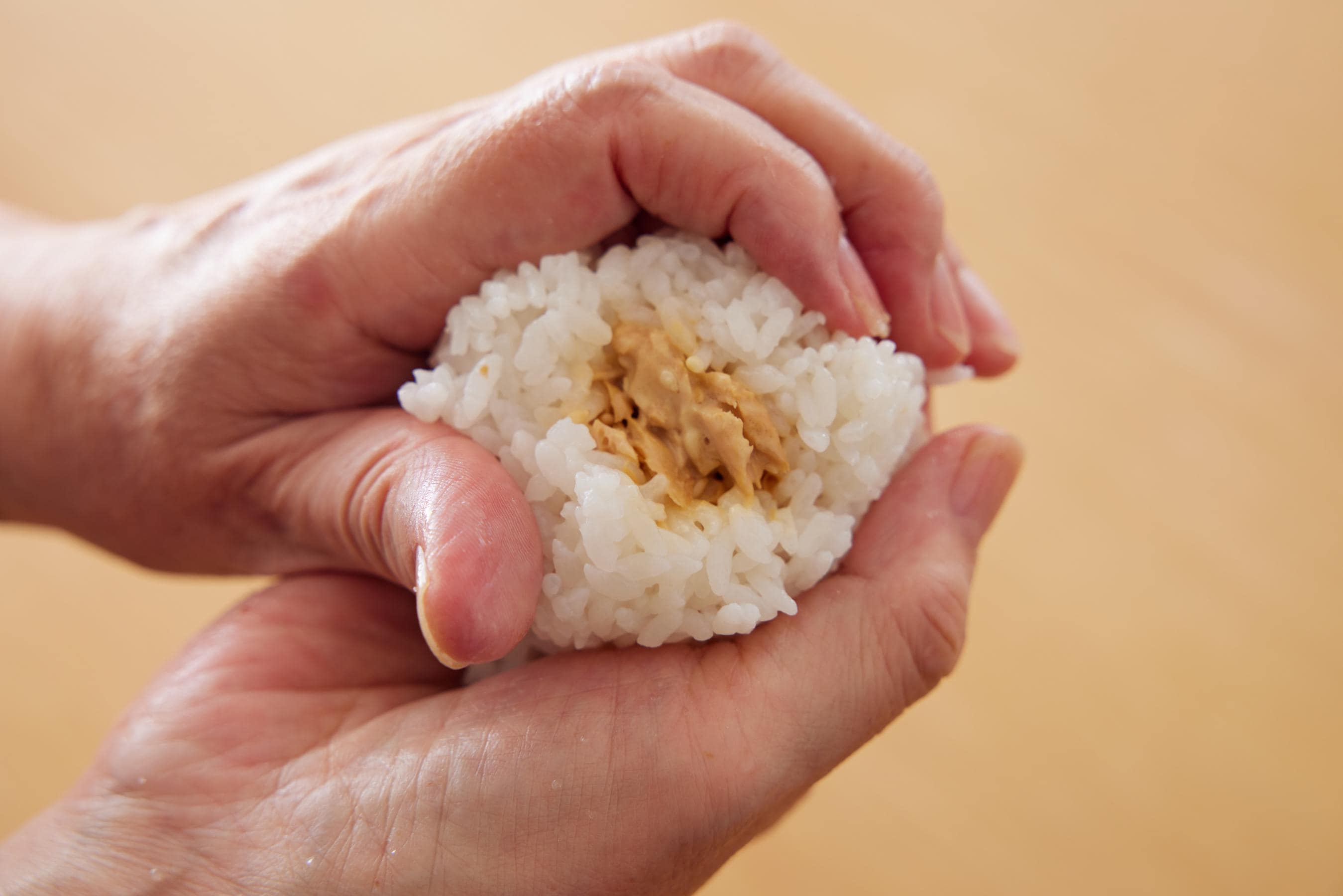 squeezing the rice ball into a triangular shape