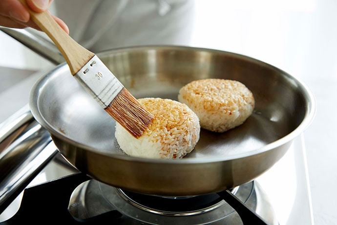 Brushing onigiri with Kikkoman Soy Sauce before grilling