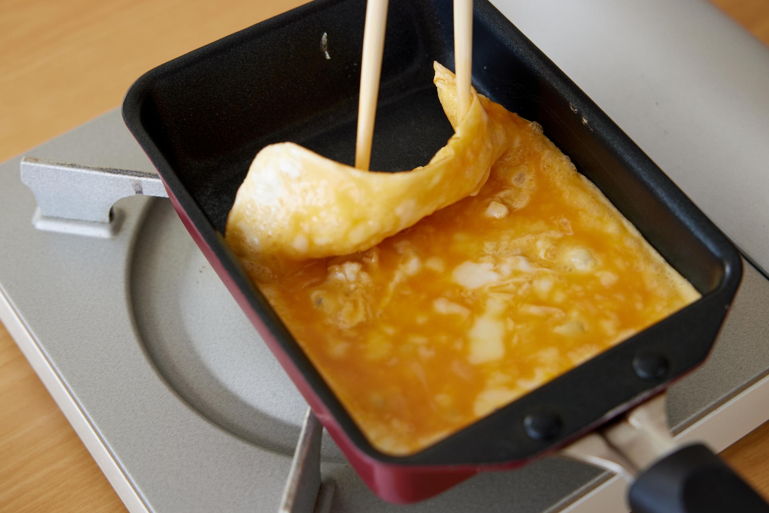 Lift up the fried egg from the far edge of the pan with chopsticks.