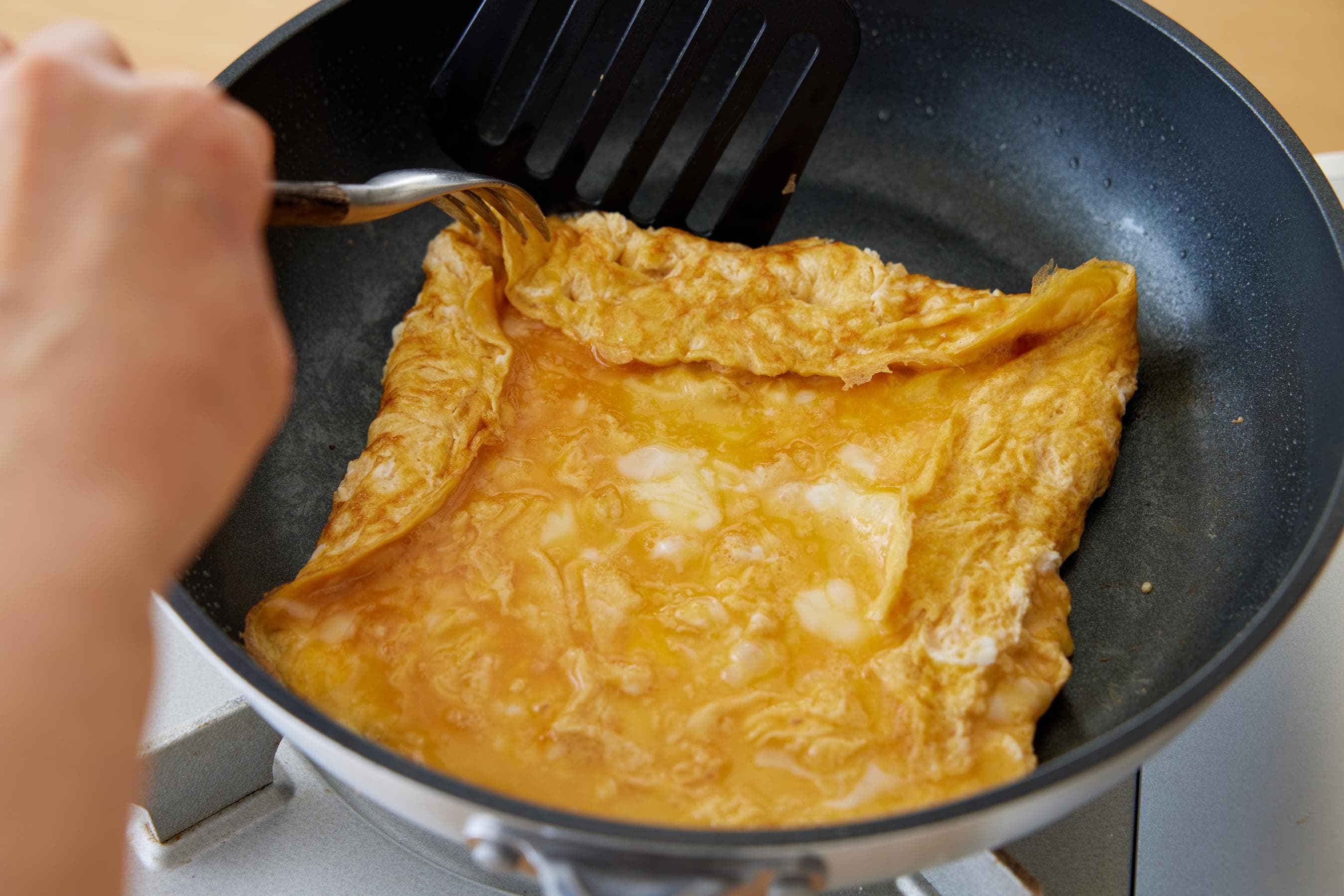 Lift and fold the far edge of the fried egg.