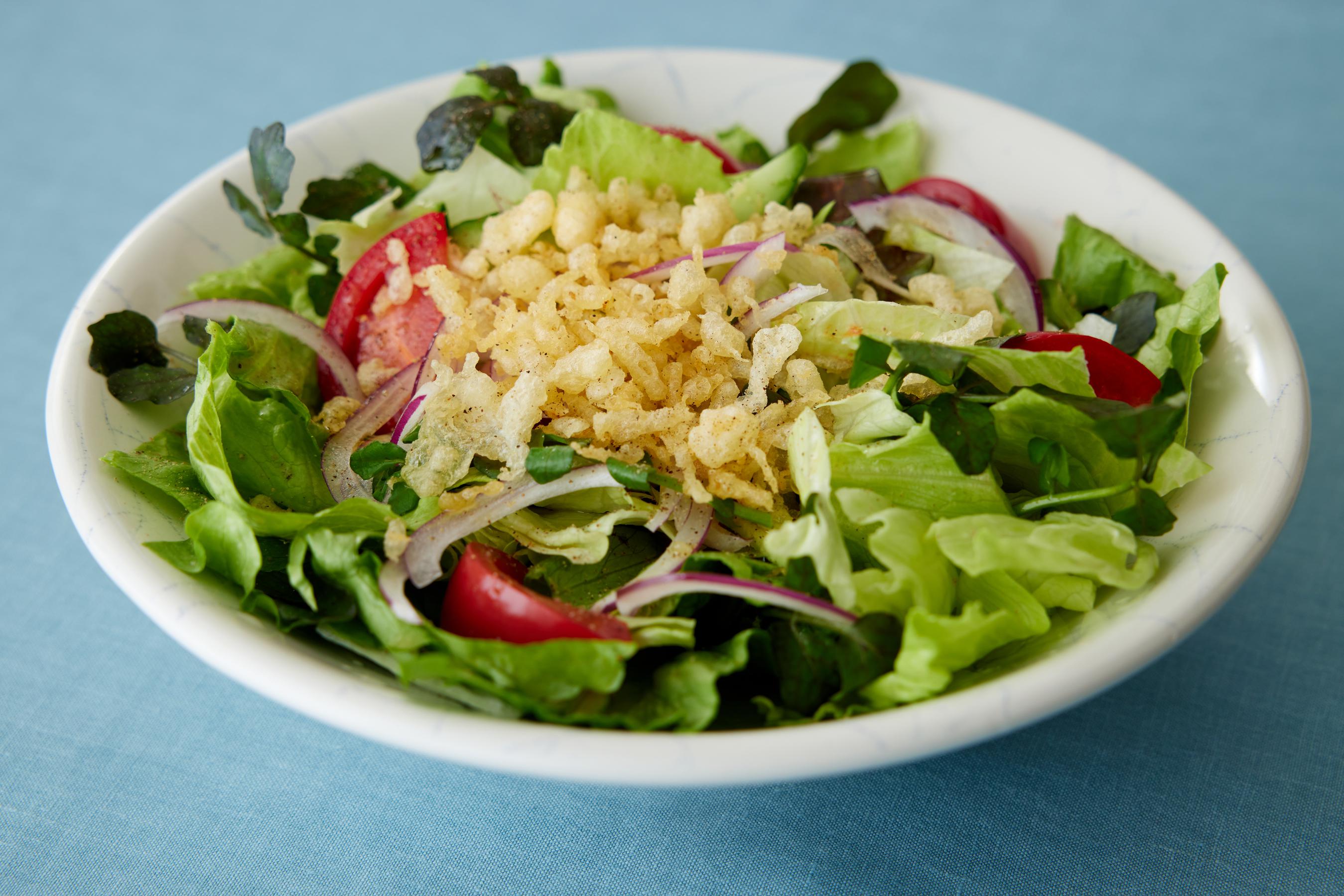 A salad topped with Tempura crumbs.