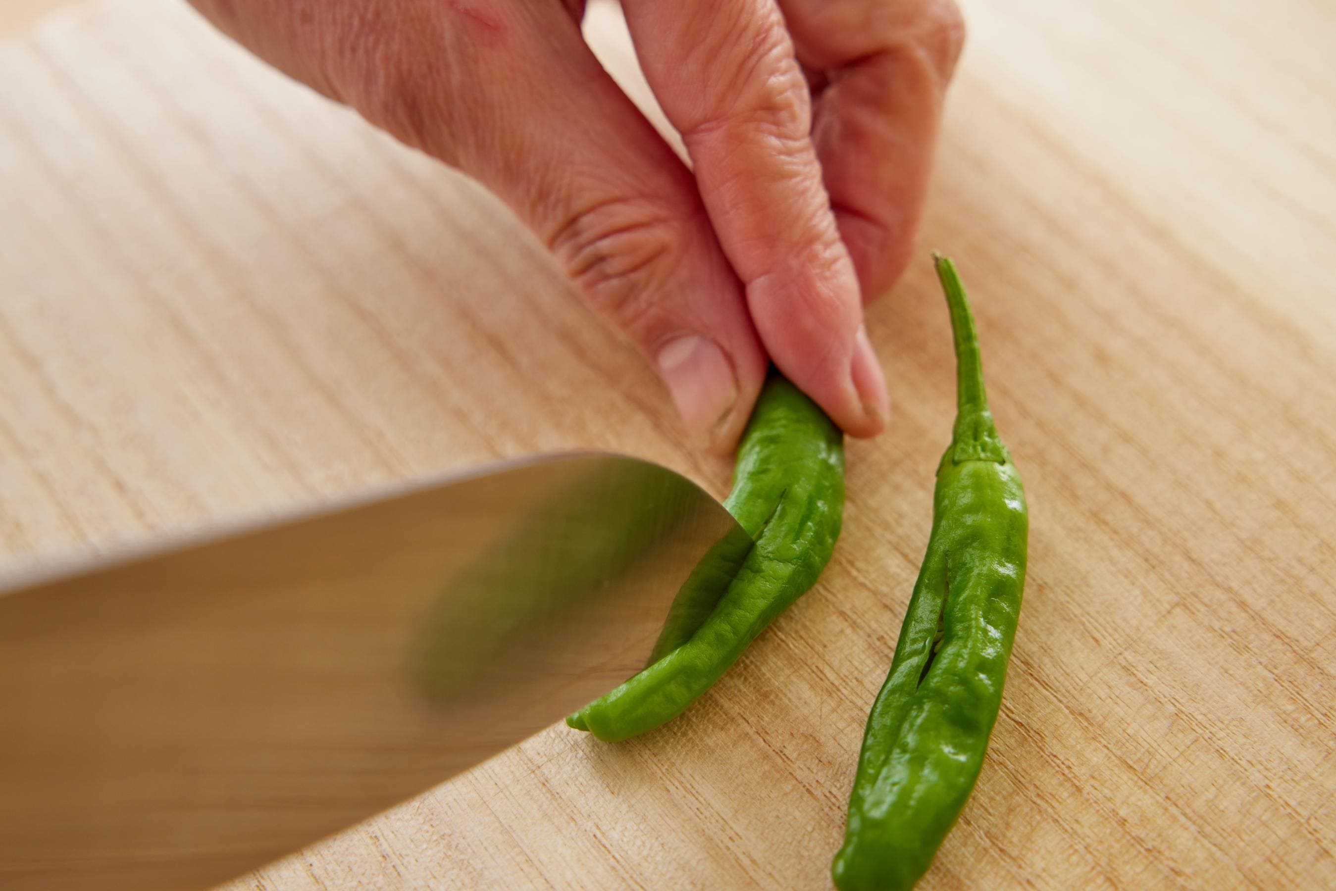 Cuting a slit in shishito peppers.