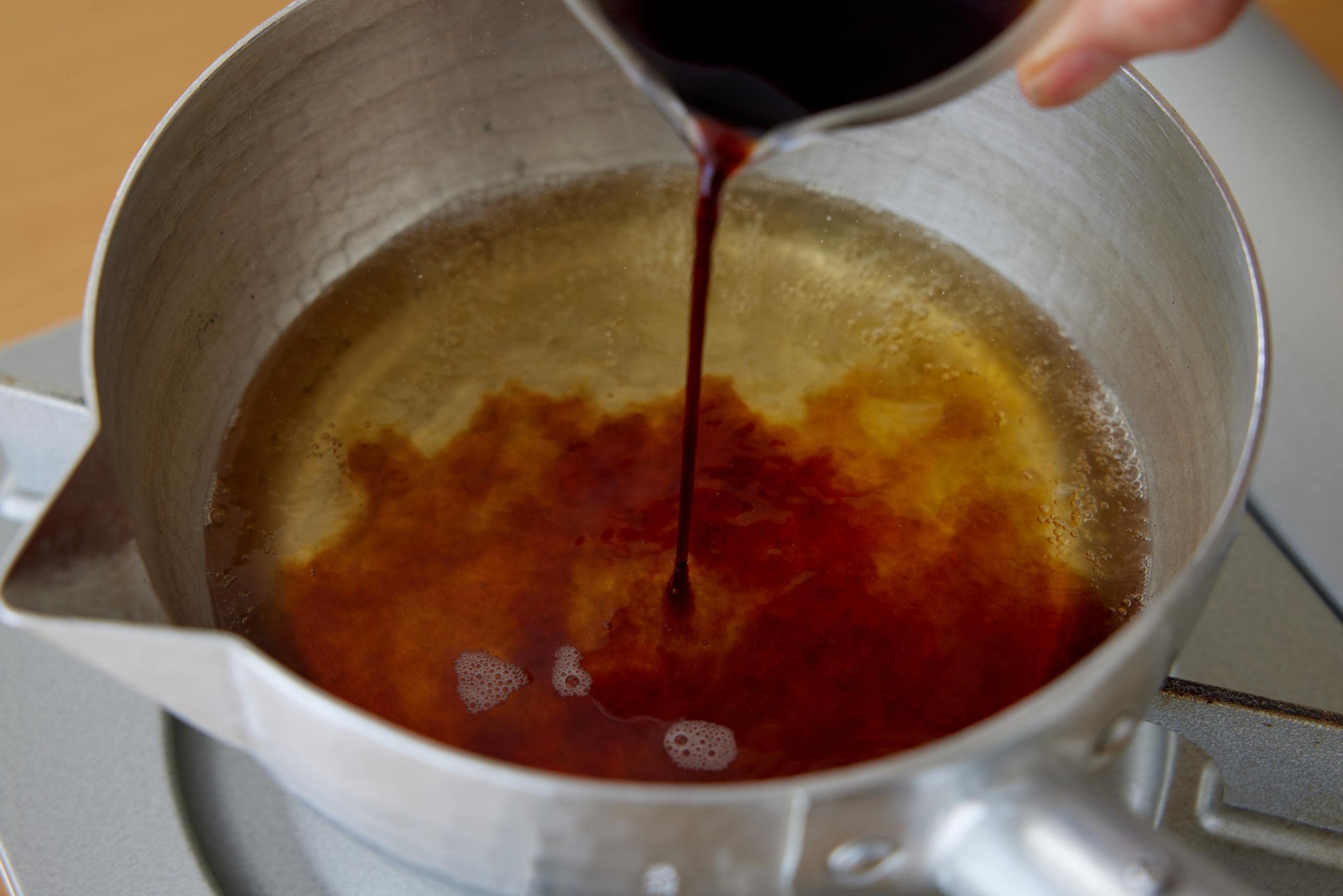 Pouring soy sauce and mirin into dashi broth.