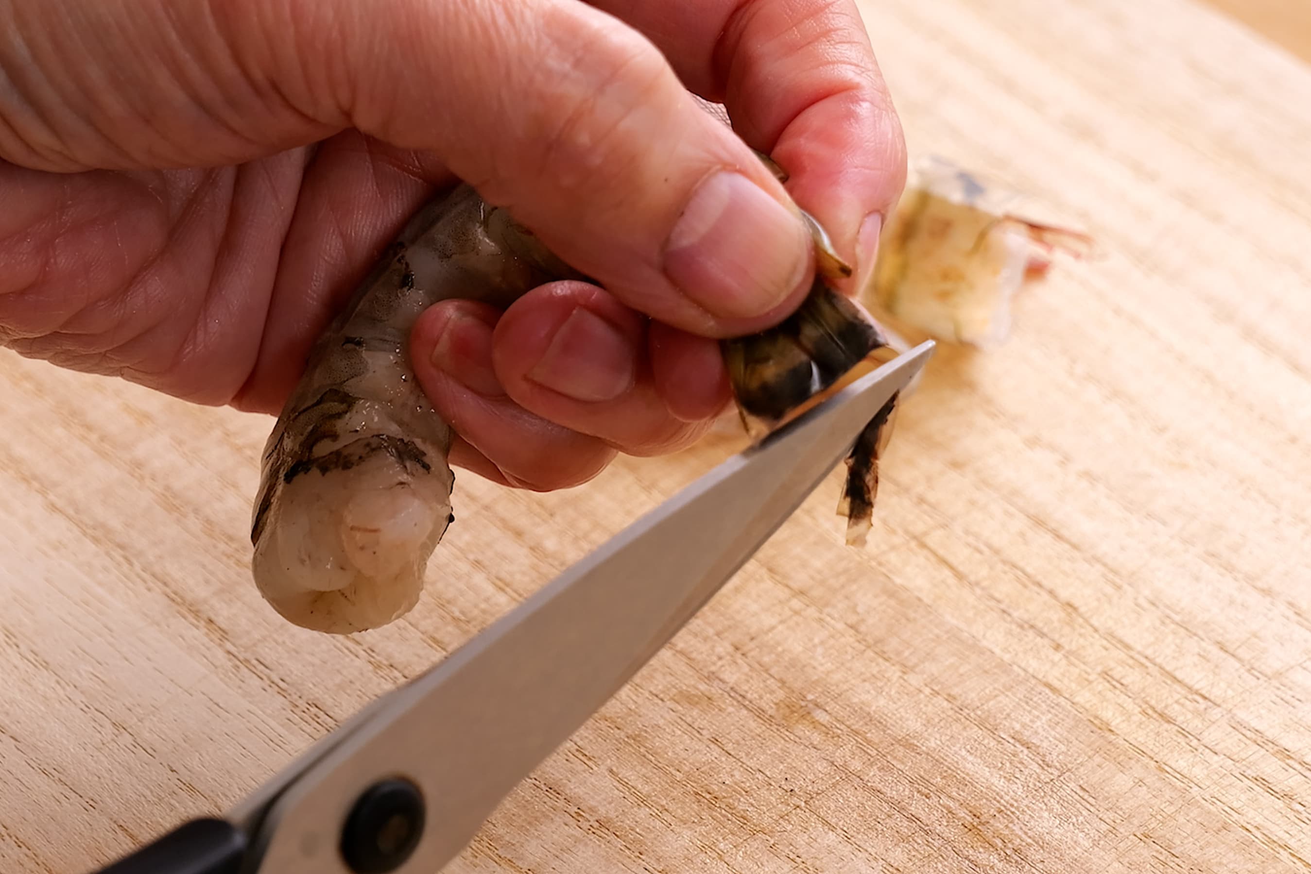 Cutting off the tip of the shrimp tail.